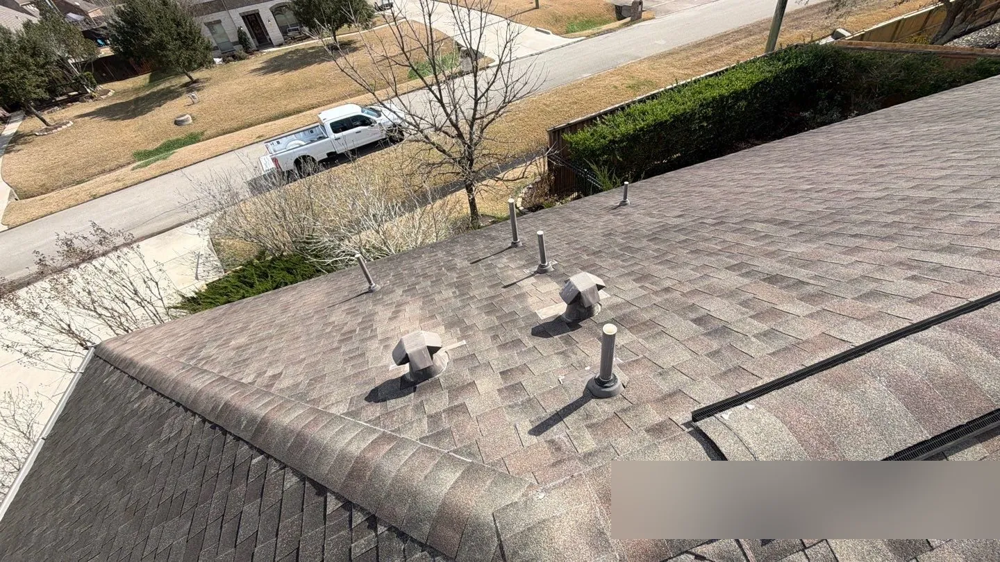 Shingle roof with two gray 4-way exhaust caps among the plumbing vent pipes