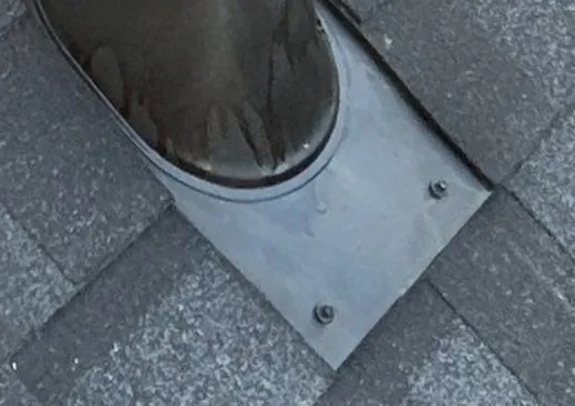 Metal flashing flange around a roof penetration, fastened flat with screws and rubber washers